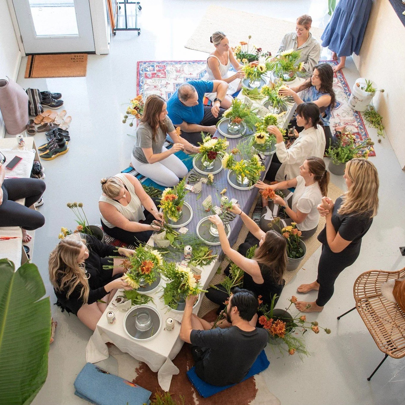Group of people learning DIY floristry, arranging flowers together in a hands-on floral design workshop.
