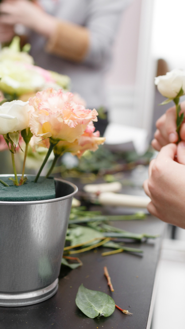 Group of people learning DIY floristry, arranging flowers together in a hands-on floral design workshop.
