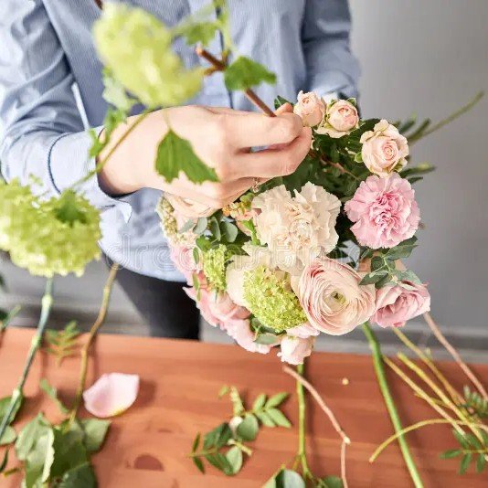 Group of people learning DIY floristry, arranging flowers together in a hands-on floral design workshop.