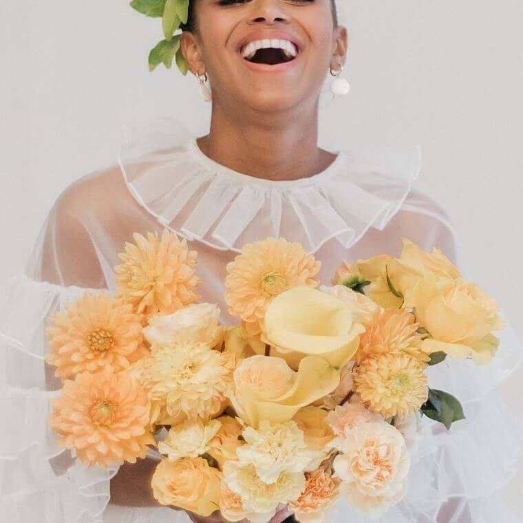 Smiling bride holding a beautiful wedding bouquet, radiating joy and elegance on her special day.