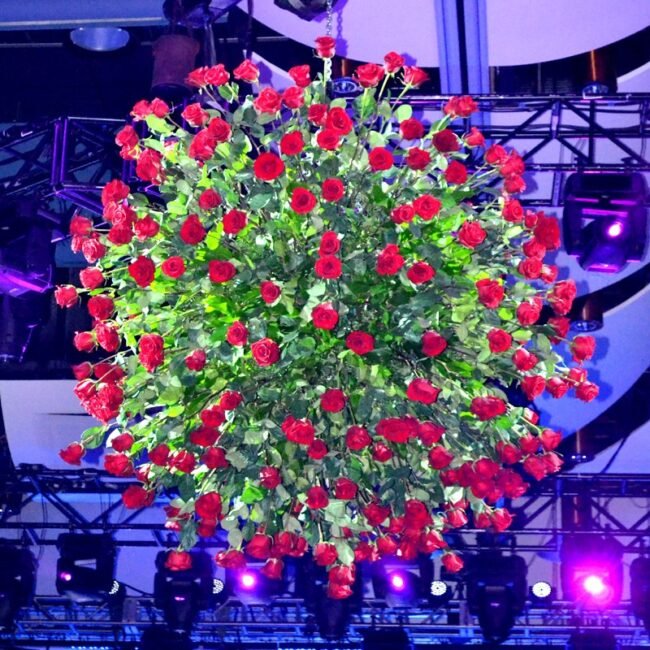 Massive spherical floral installation completely covered in stunning red roses for a dramatic event centerpiece.