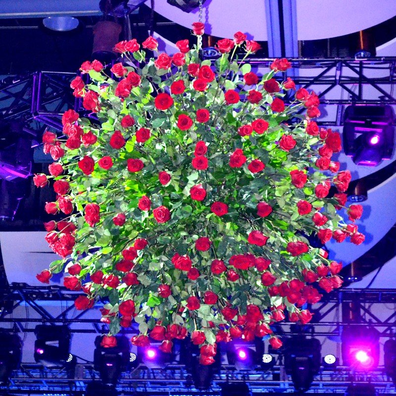 Massive spherical floral installation completely covered in stunning red roses for a dramatic event centerpiece.