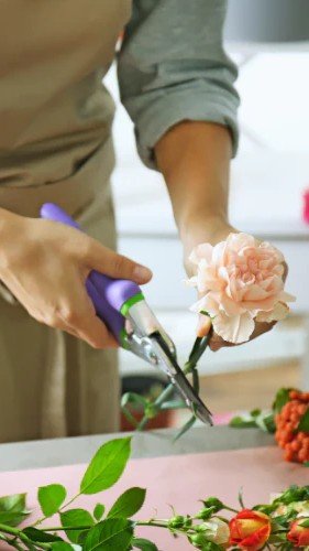 Florist arranging fresh flowers in a workshop, showcasing creative floral design in progress.