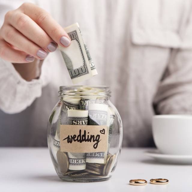 "Glass jar labeled for wedding savings, used to collect money for planning and budgeting a celebration.